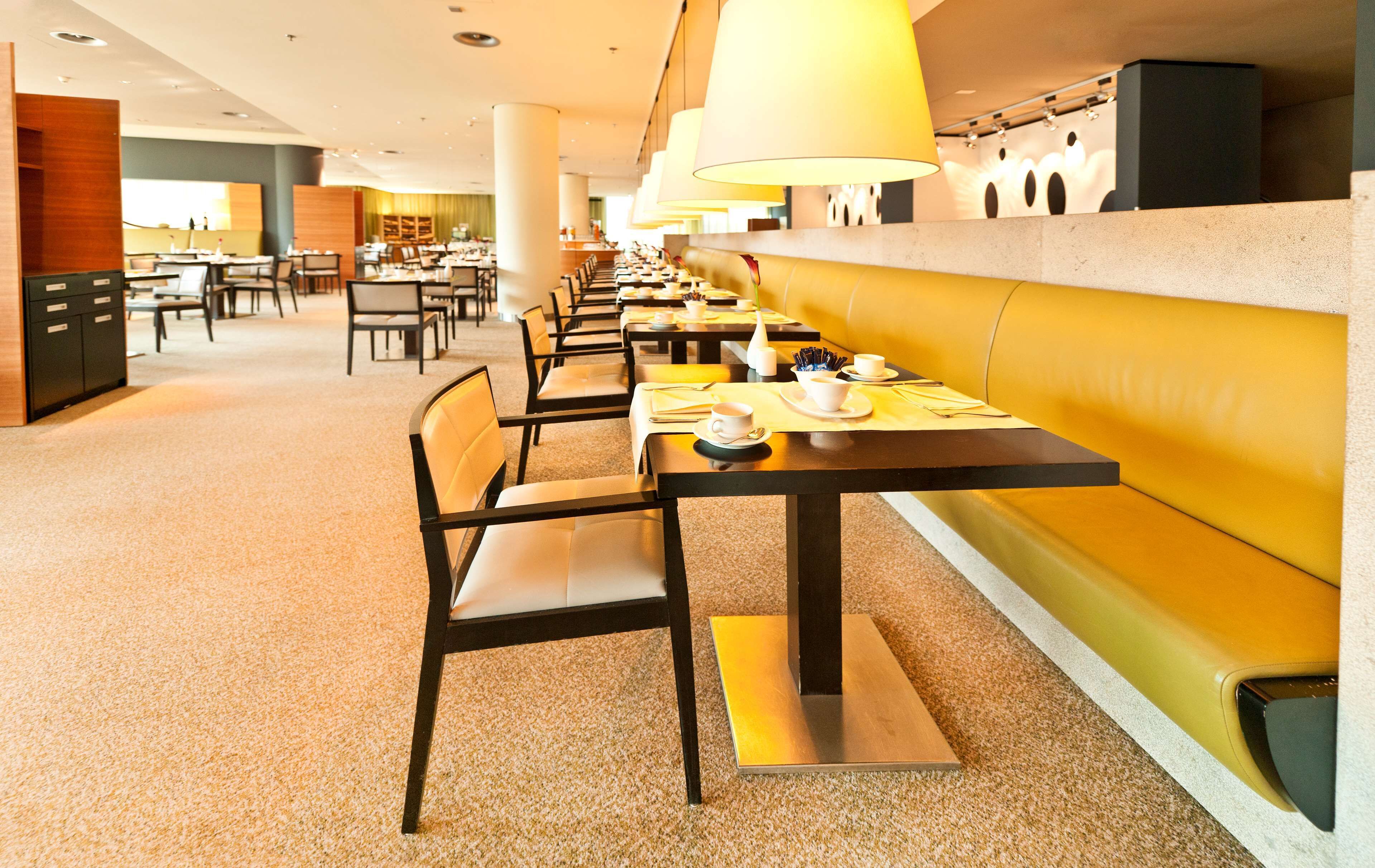 A modern dining area with long tables, chairs, and a yellow booth.
