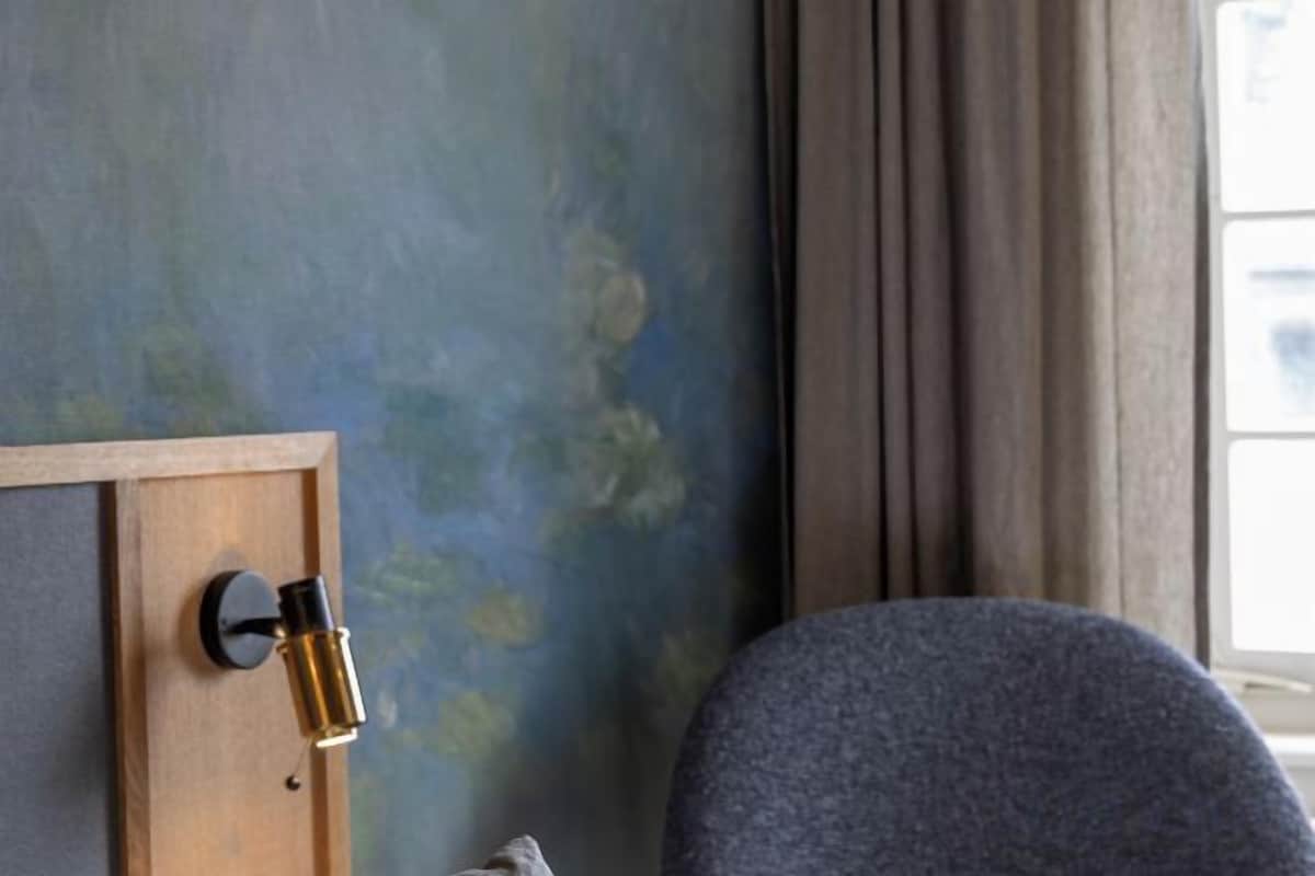 Una habitación con puerta de madera, una silla azul y una ventana con cortinas.