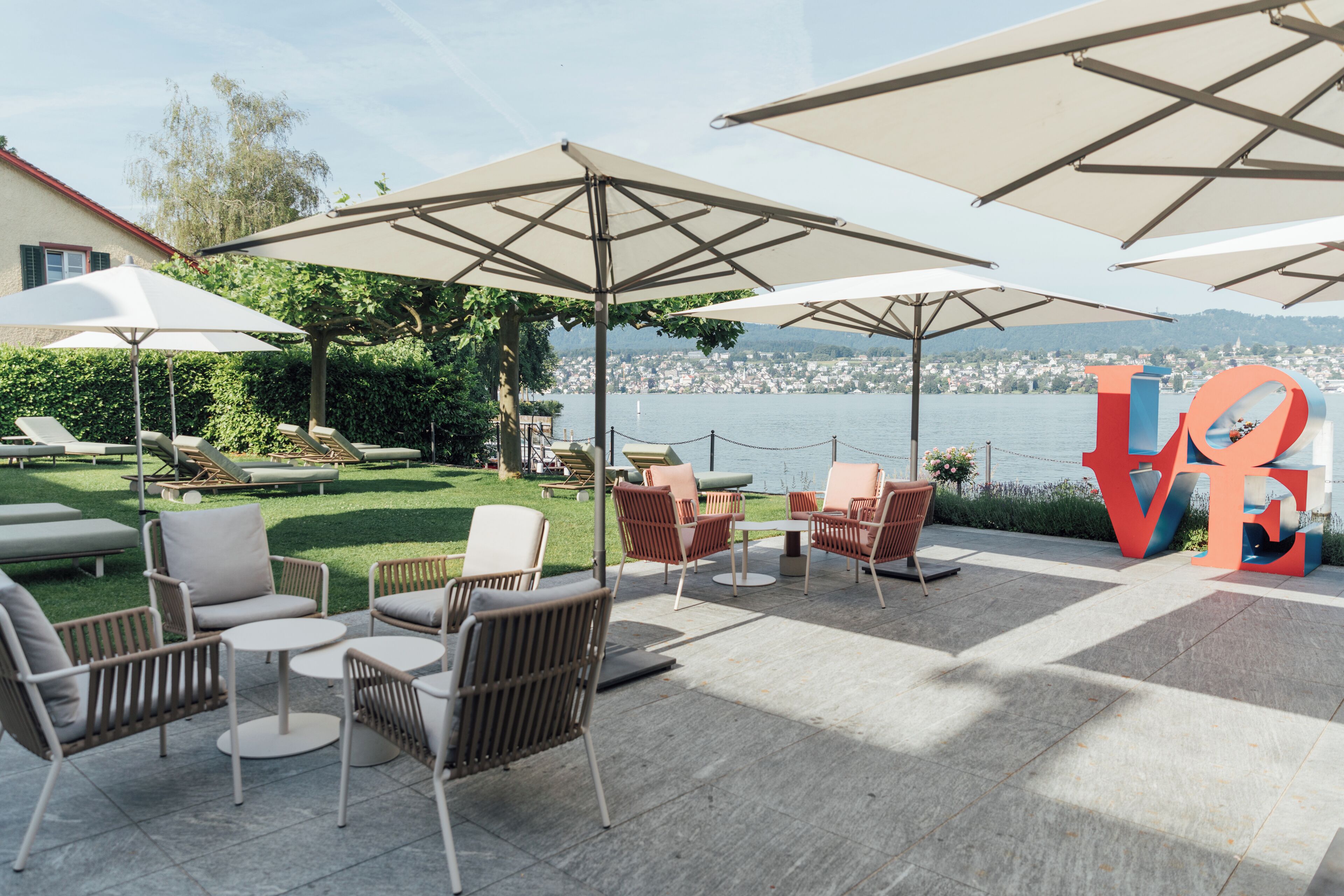 An outdoor seating area with umbrellas, lounge chairs, and a view of a body of water.