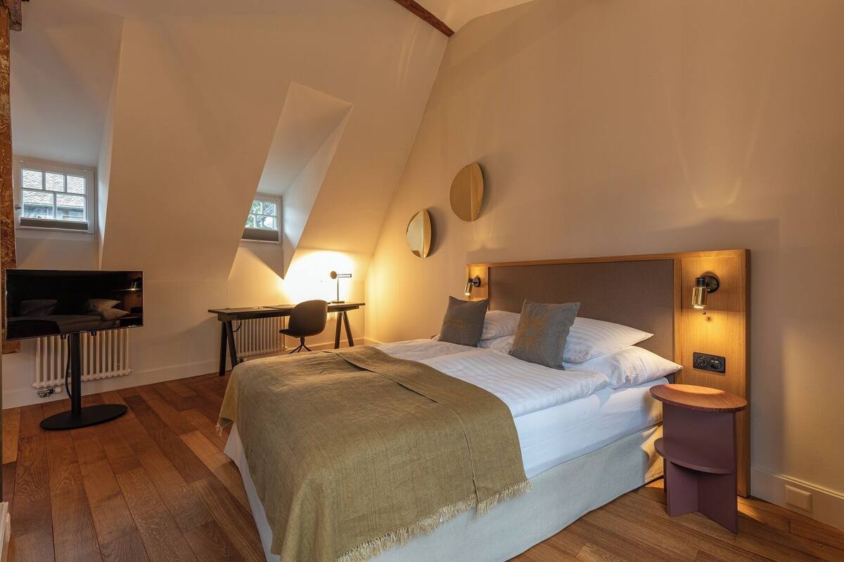 A bedroom with a bed, a desk, a chair, and a nightstand.