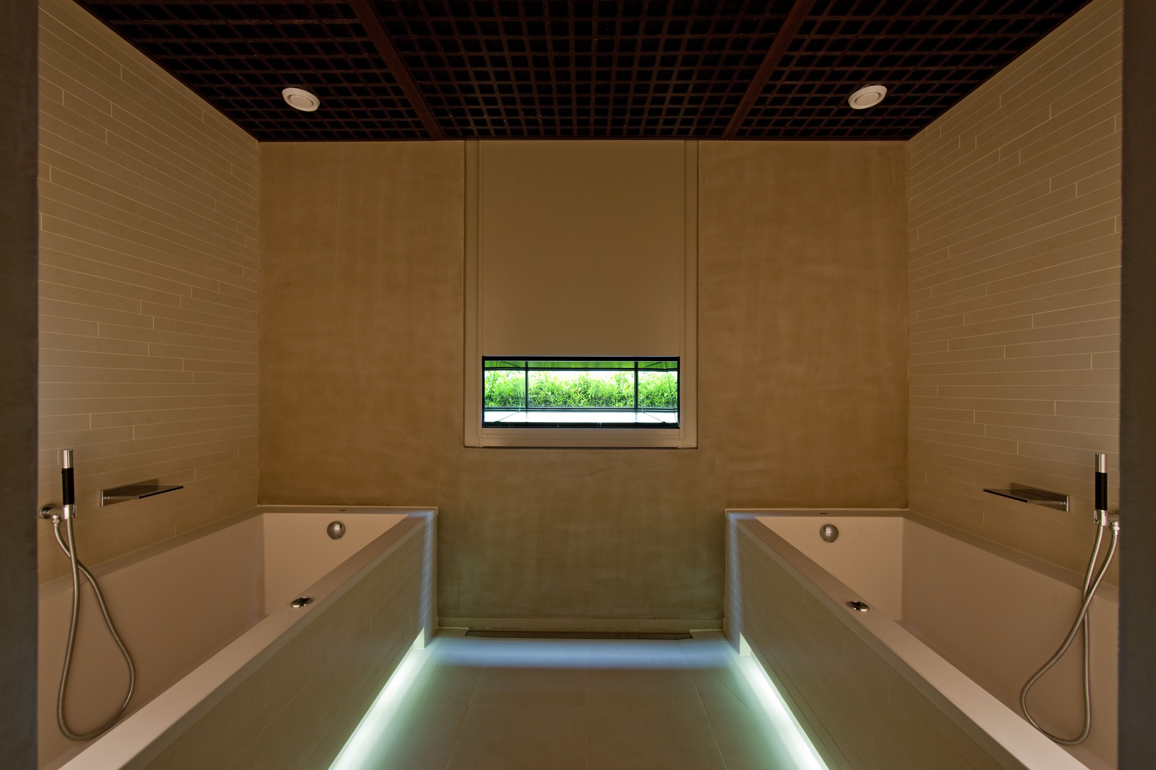 Un baño moderno con dos bañeras separadas, una ventana con vistas y un techo con diseño de cuadrícula.