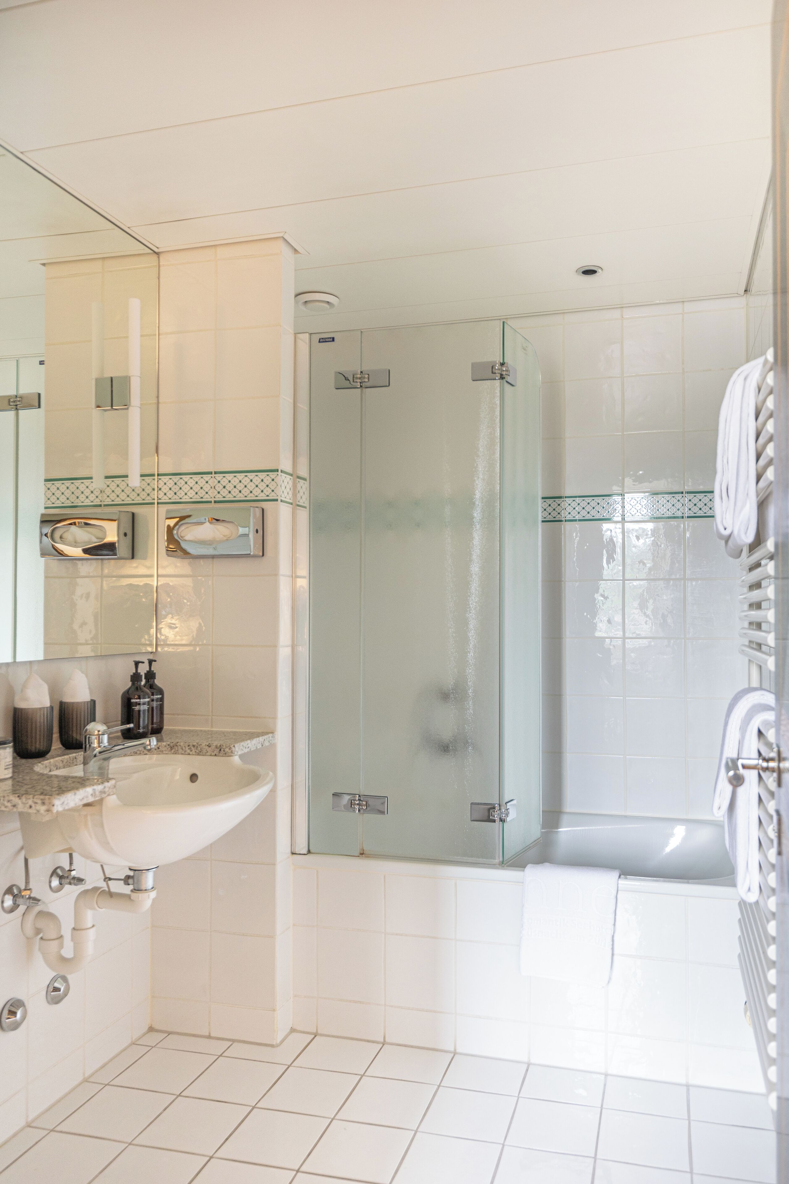 A modern bathroom with a glass-enclosed shower, a white sink, and a large mirror.