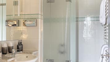 A modern bathroom with a glass-enclosed shower, a white sink, and a large mirror.