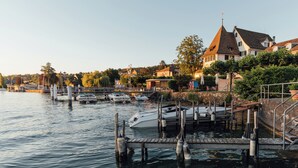 A marina with docked boats, a wooden dock, and houses in the background. - Seehotel Sonne (Kuesnacht)