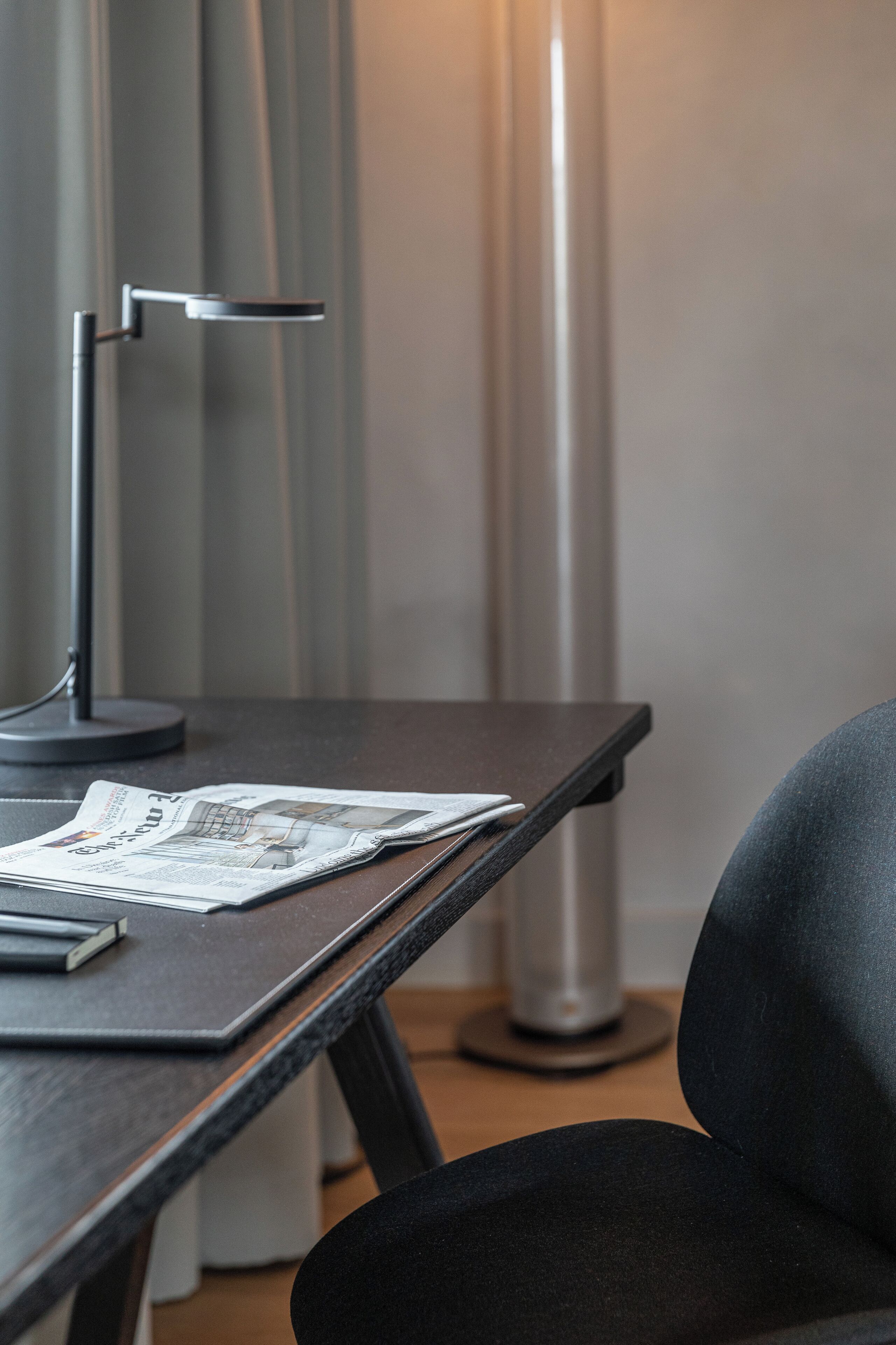 Un bureau moderne avec une lampe, une chaise et quelques documents.