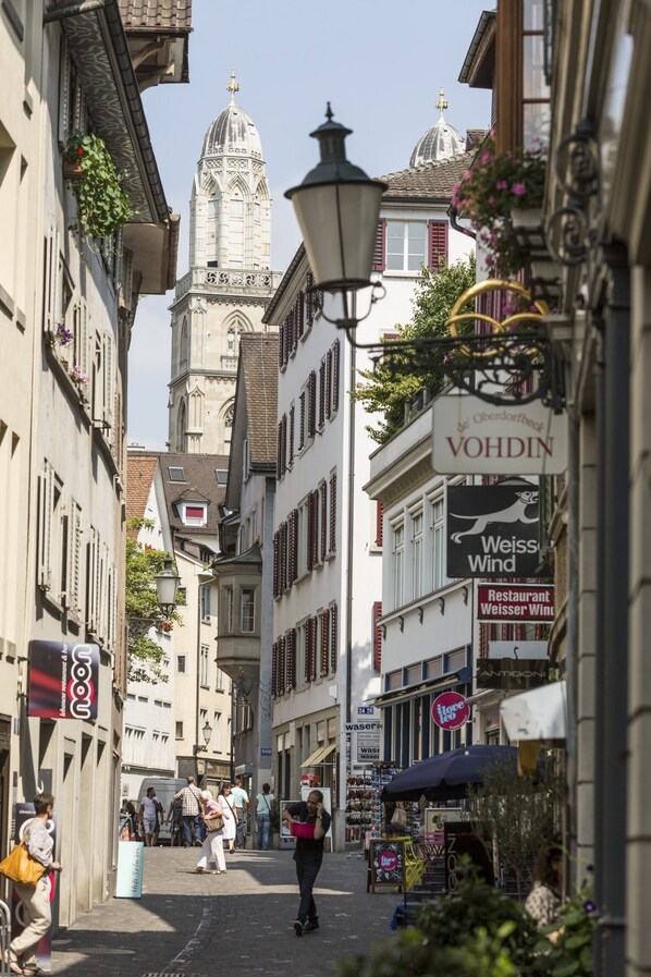 A narrow street with historic buildings, a prominent tower, and various shops and signs. - Seehotel Sonne (Kuesnacht)