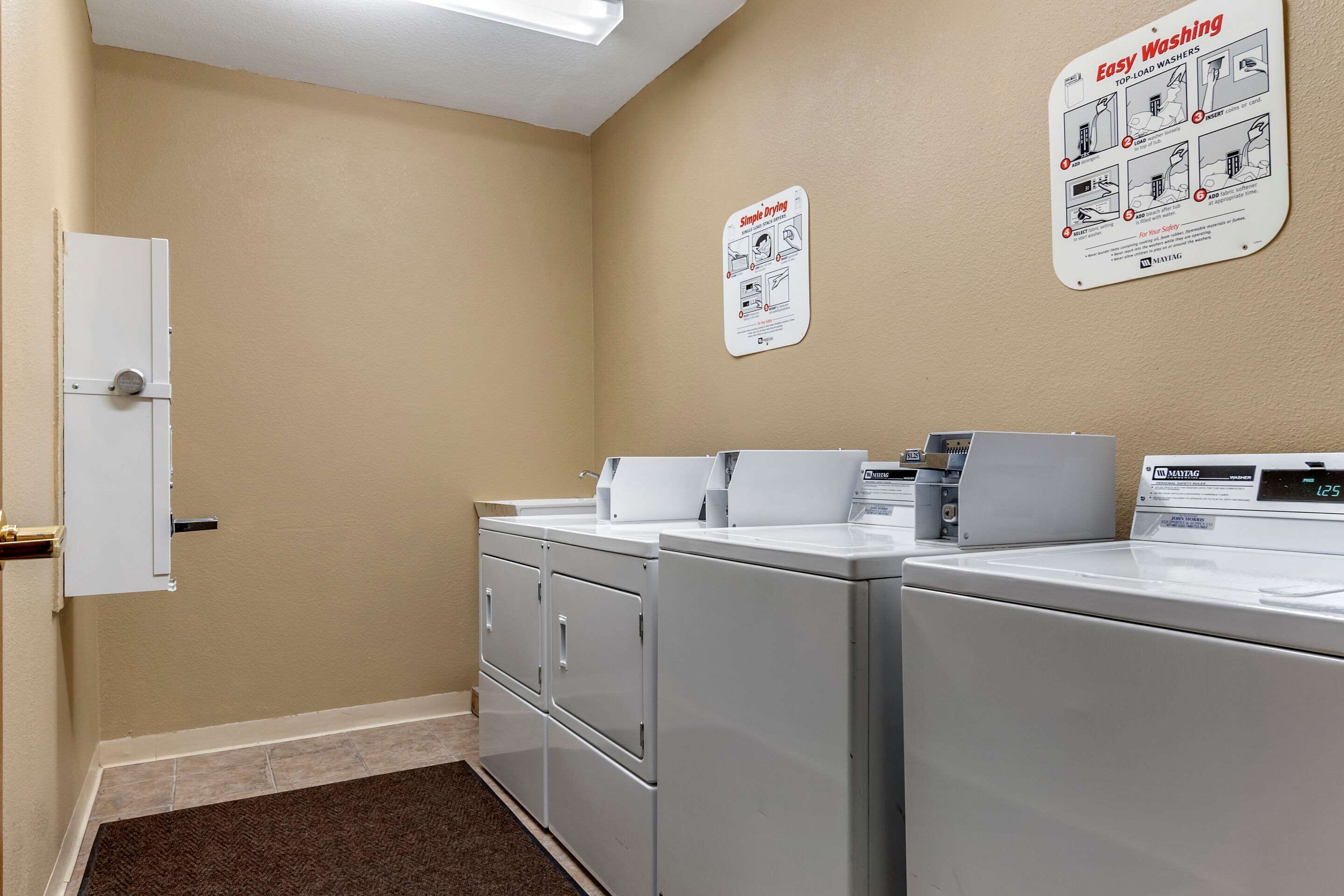 A laundry room with a white washing machine, a dryer, and a wall-mounted instruction sign.