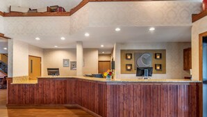 A reception area with a wooden reception desk, a clock, and framed pictures on the wall. - Comfort Inn Warrensburg Station (Warrensburg)