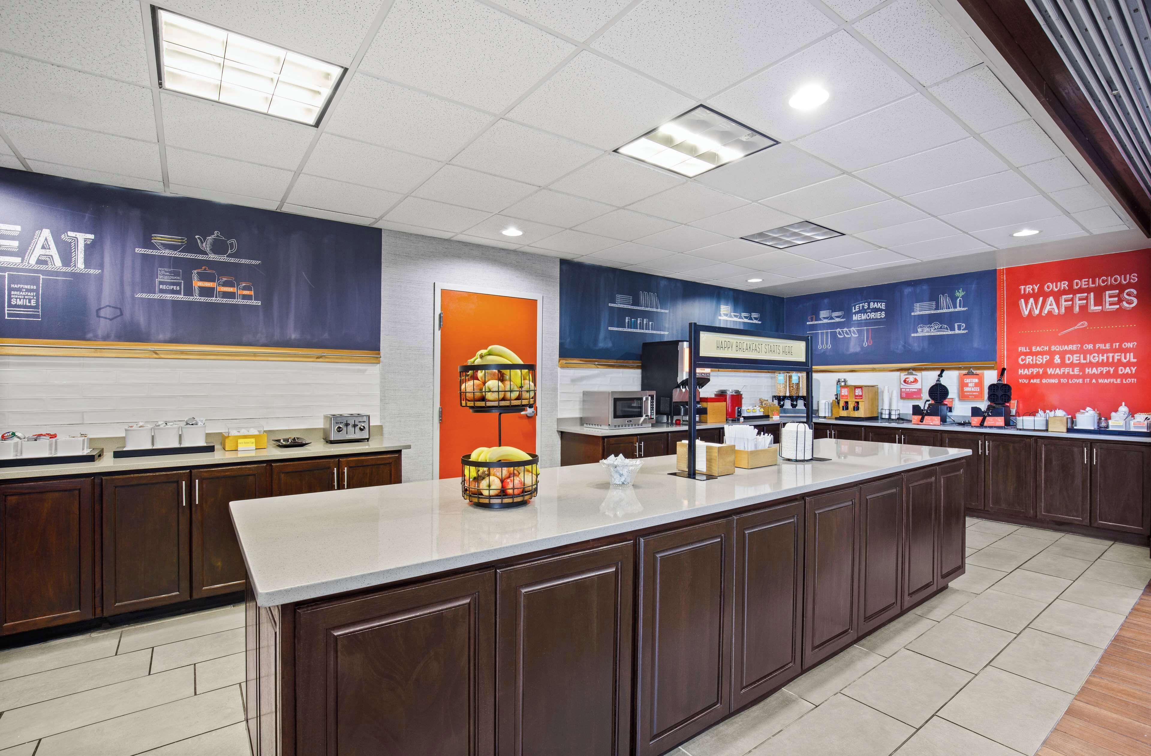 A modern kitchen with a central island, wooden cabinets, and a bright color scheme.