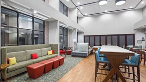 Un espace de détente moderne comprenant un canapé, des poufs, une table basse et une table à manger avec des chaises.