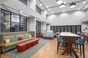 Un espacio lounge moderno con sofá, otomanas, una mesa de centro y una mesa de comedor con sillas.
