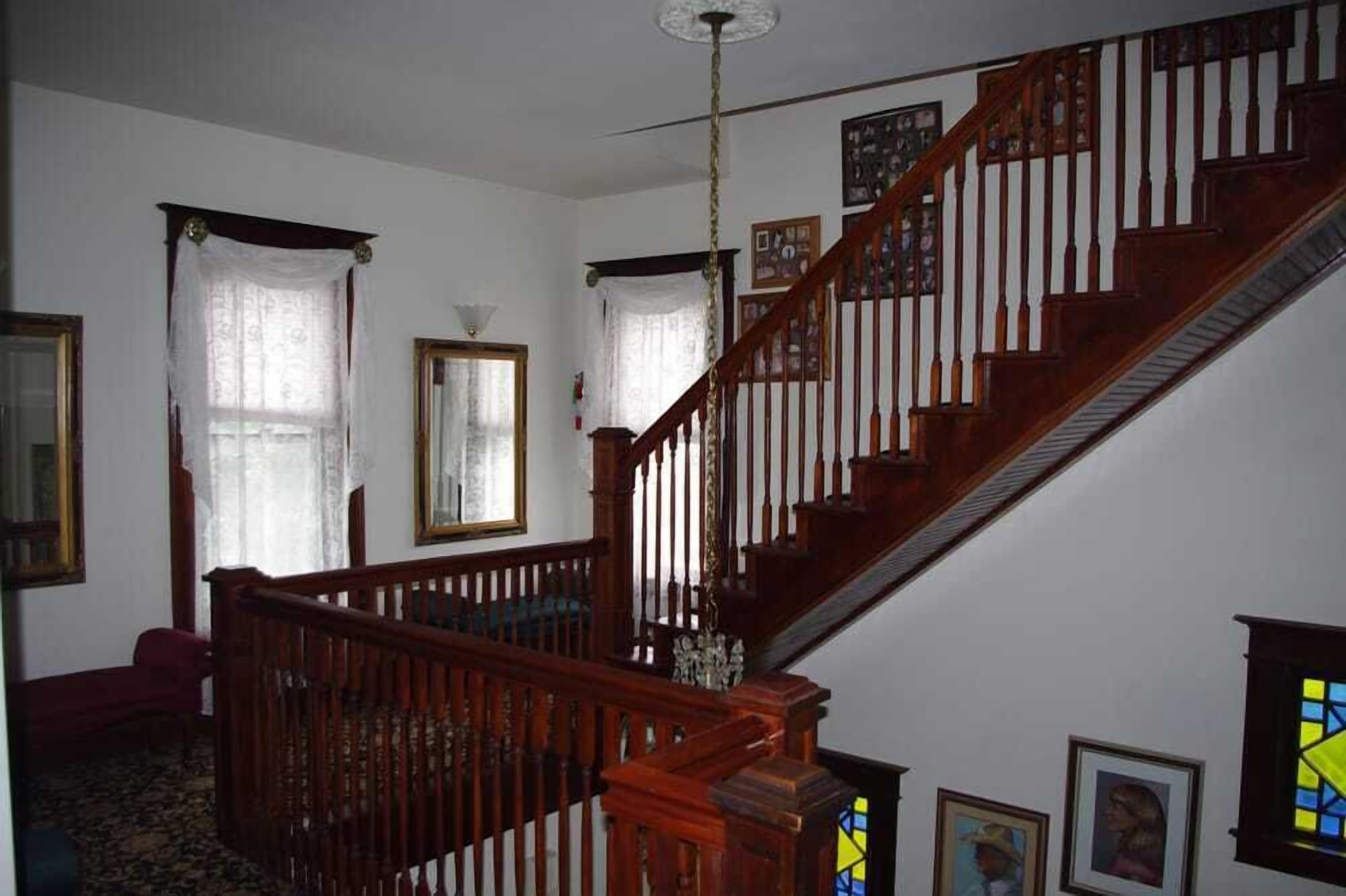 A staircase with wooden railings and a chandelier, leading to an upper floor.