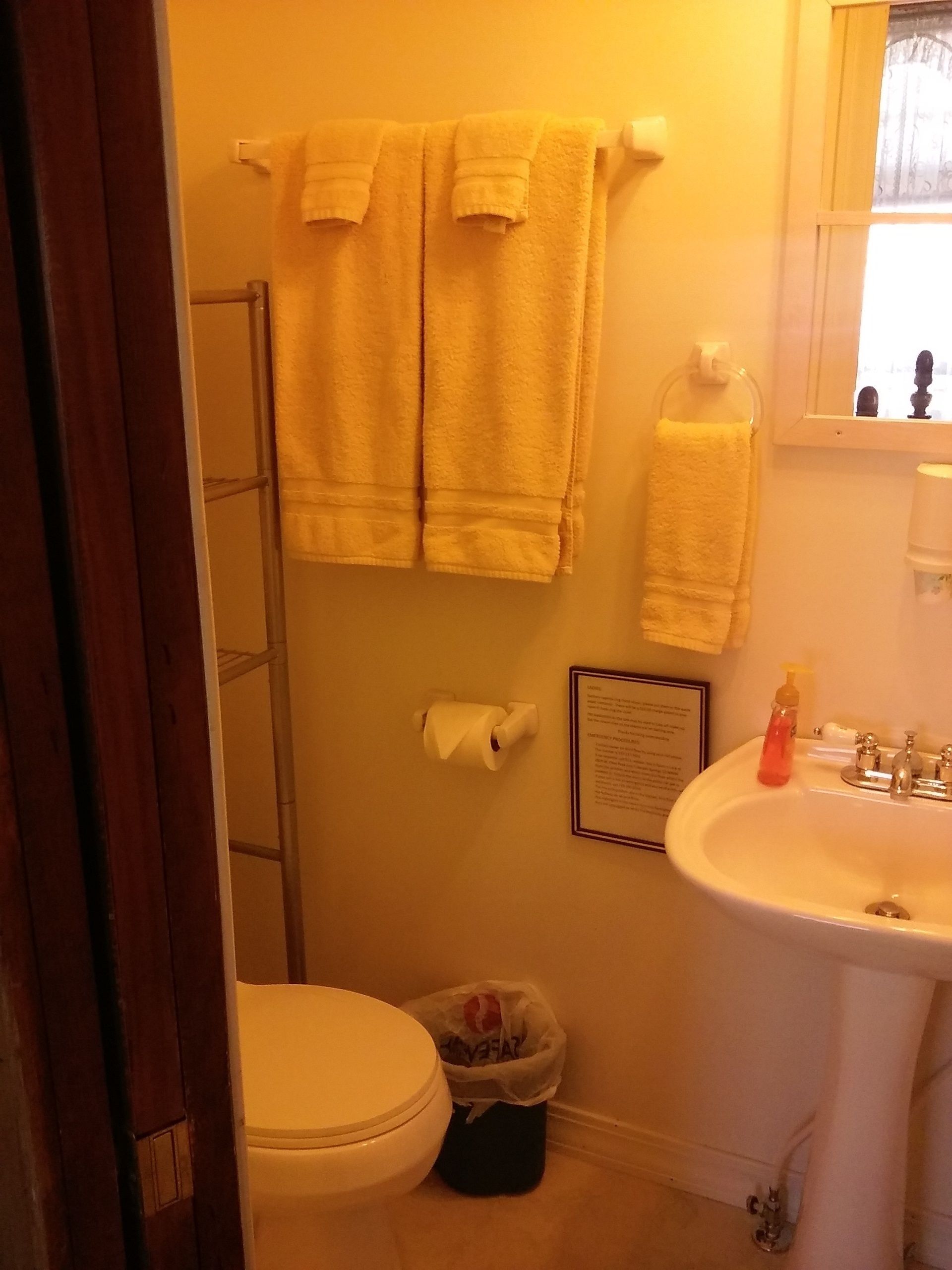 A bathroom with a toilet, sink, and two towels hanging on the wall.