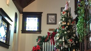 A staircase with a Christmas tree decorated with ornaments and a garland. - Spurs n Lace Bed & Breakfast Inn (Colorado Springs)