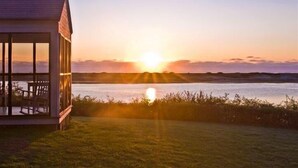 A modern building with large windows overlooking a body of water during sunset. - Dunes on the Waterfront (Ogunquit)