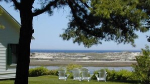 A grassy area with outdoor seating and a view of the ocean. - Dunes on the Waterfront (Ogunquit)
