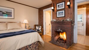 A bedroom with a bed, a fireplace, and a door leading to another room. - Dunes on the Waterfront (Ogunquit)