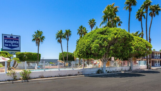 A Knights Inn & Suites with a view of the ocean, palm trees, and a fenced pool area.