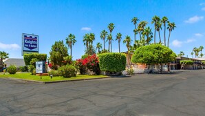 A hotel named Knights Inn & Suites with a clear blue sky, palm trees, and well-maintained landscaping.