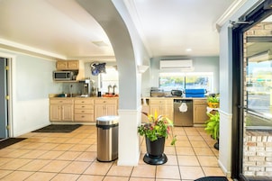 Una cocina moderna con armarios color beige, un bote de basura de acero inoxidable y una planta en maceta.