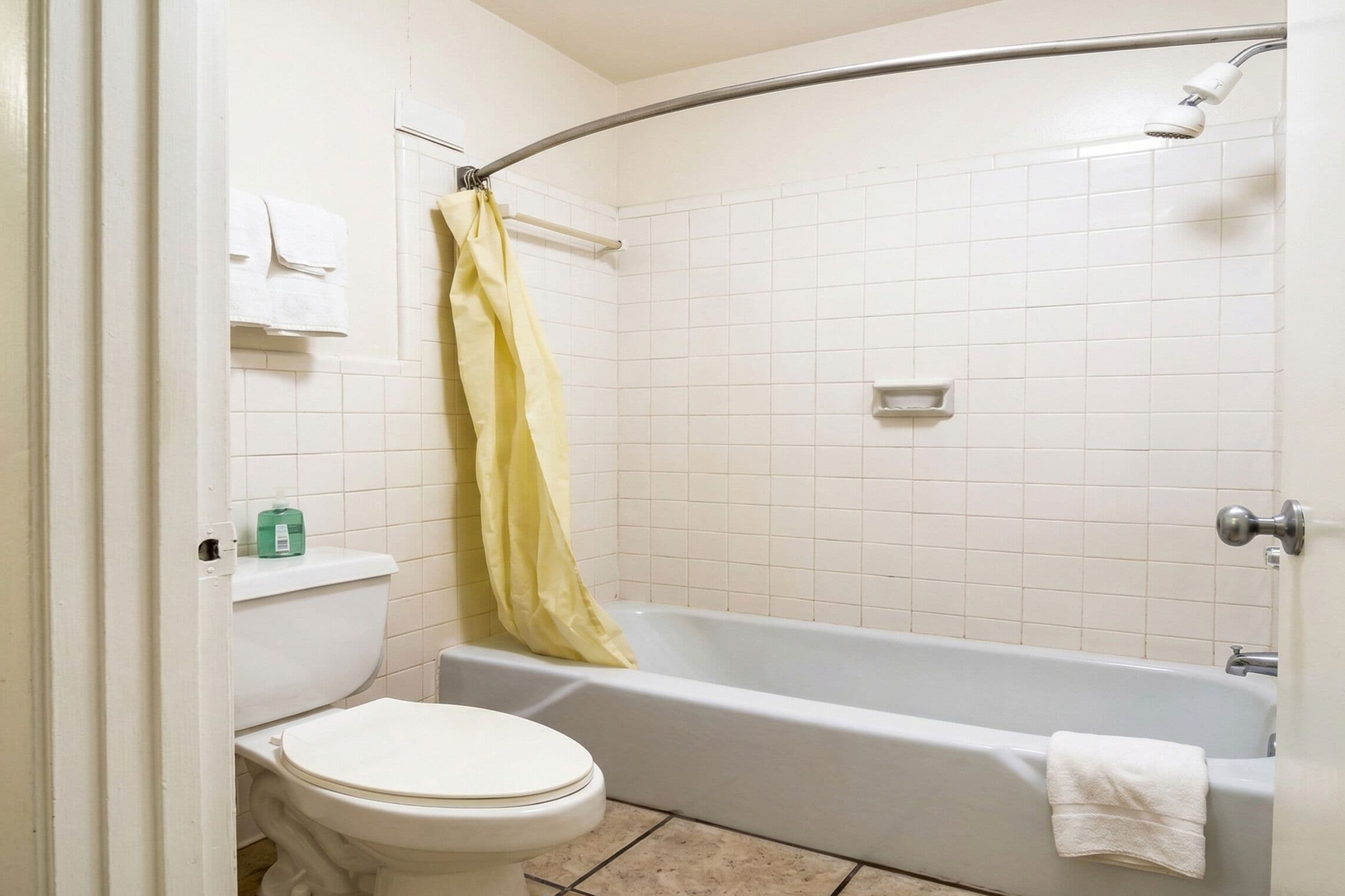 Un baño con inodoro, bañera, cortina de ducha y barra para toallas.