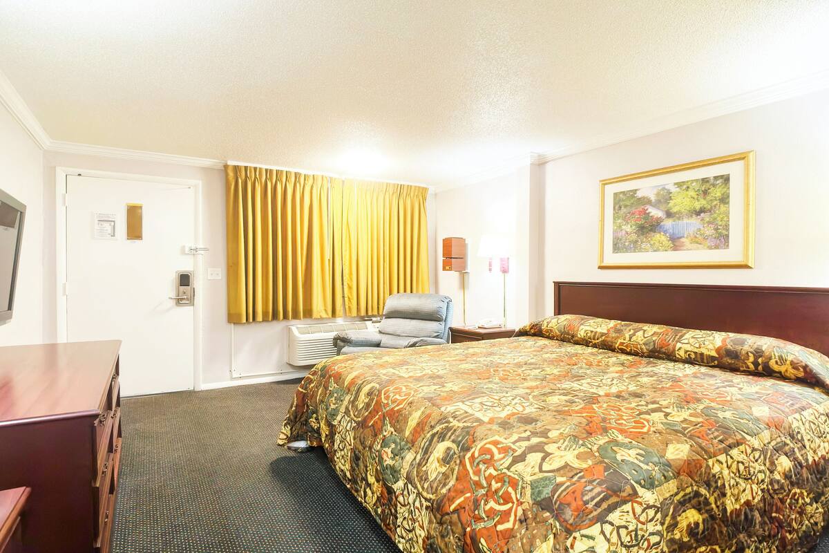 Ein Hotelzimmer mit einem großen Bett, einem Schreibtisch, einem Sessel und einem Bild an der Wand.