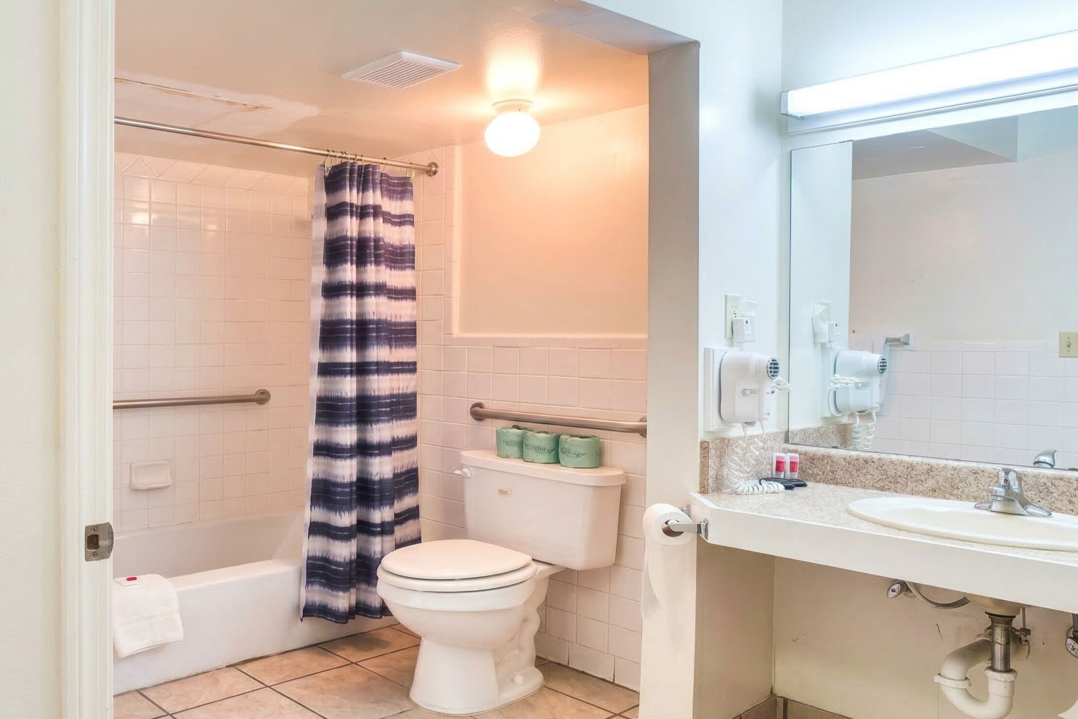 A bathroom with a shower, toilet, sink, and a mirror.