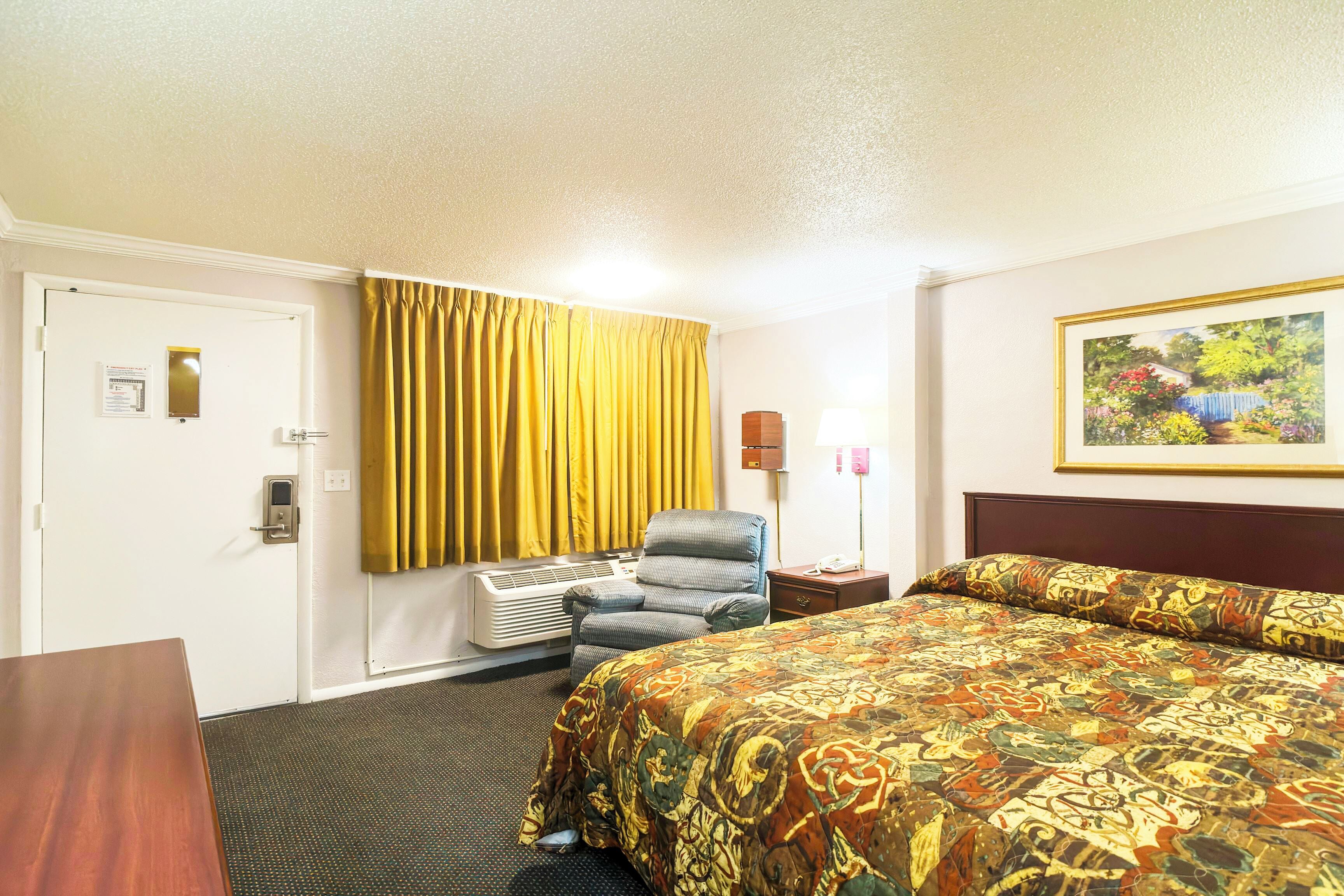 Ein Hotelzimmer mit Bett, Stuhl, Schreibtisch und Tür.