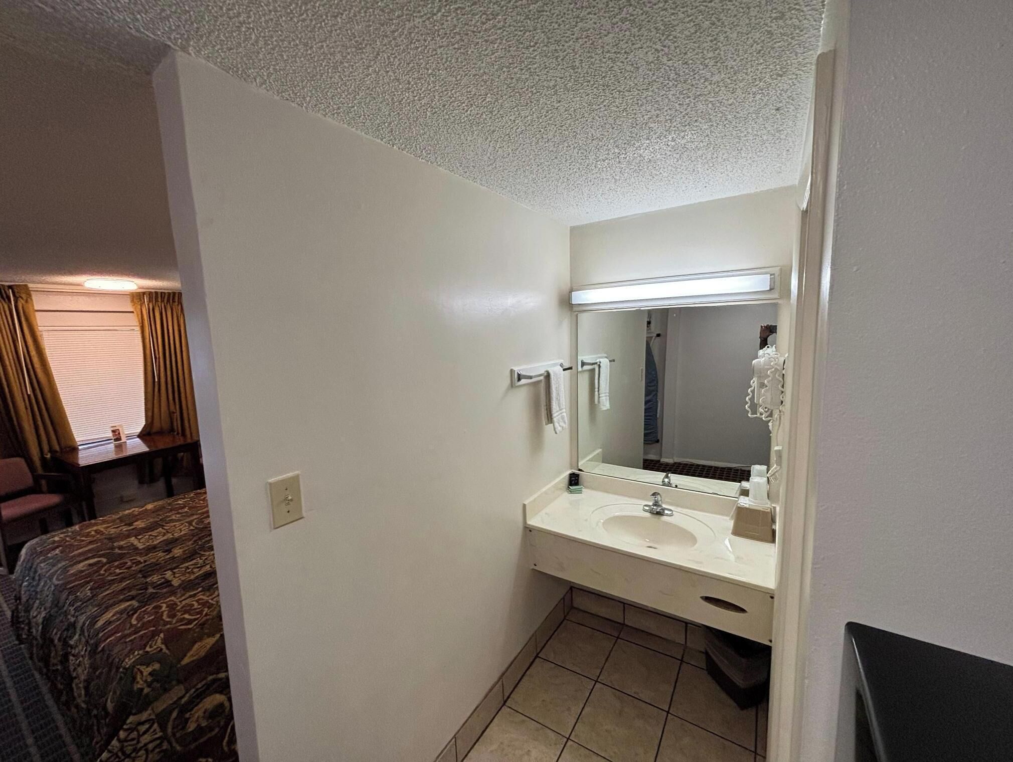 A hotel bathroom with a sink, mirror, and towel rack.