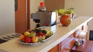 A kitchen with a fruit bowl, a potted plant, and a television on the wall. - Bella Capri Inn (Camarillo)