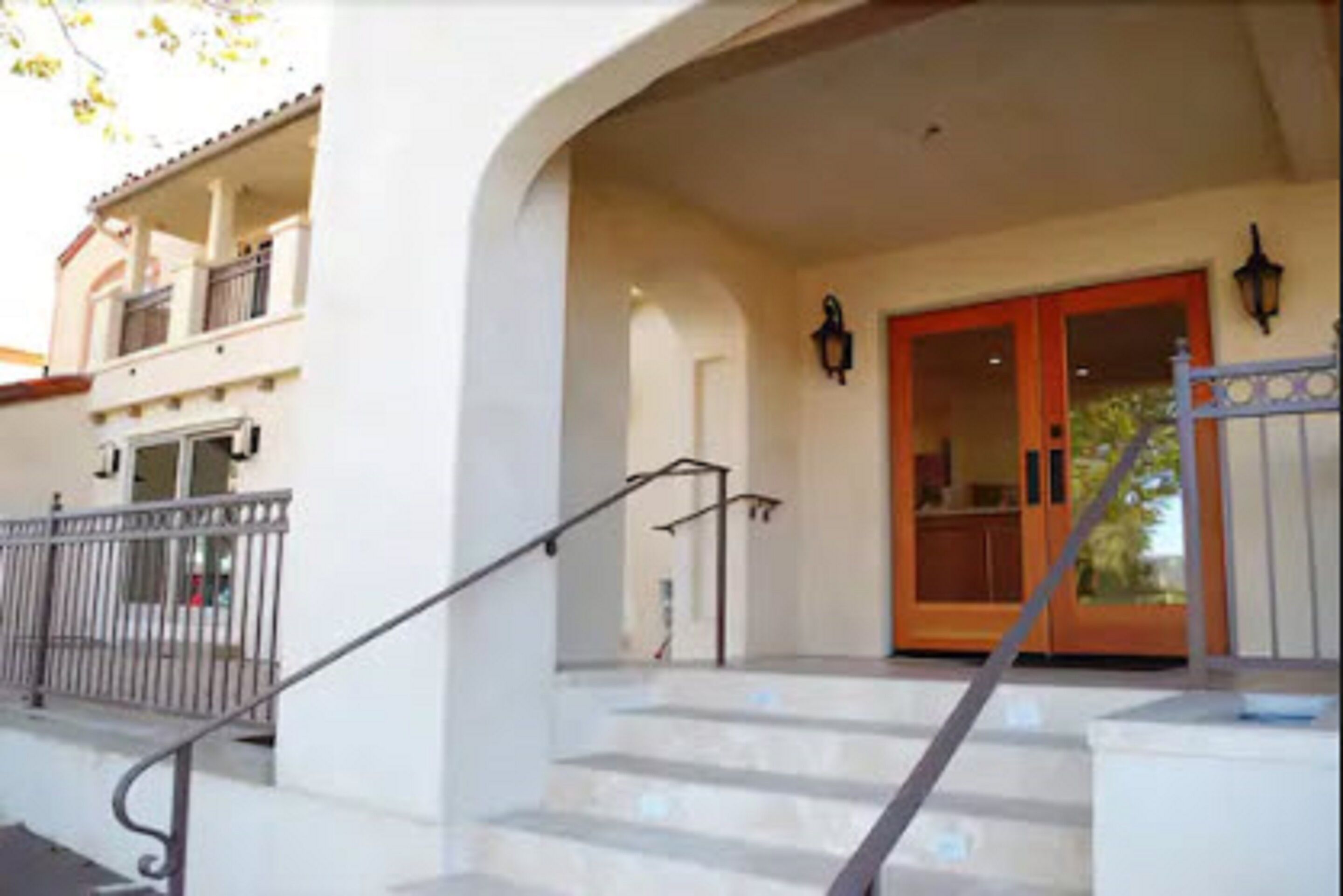 A building with a covered entrance, a staircase, and a balcony.