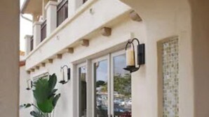 A building with a white facade, large windows, and a potted plant in the foreground. - Bella Capri Inn (Camarillo)