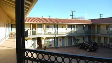 Un motel con una zona exterior cubierta, varias habitaciones y un coche aparcado.
