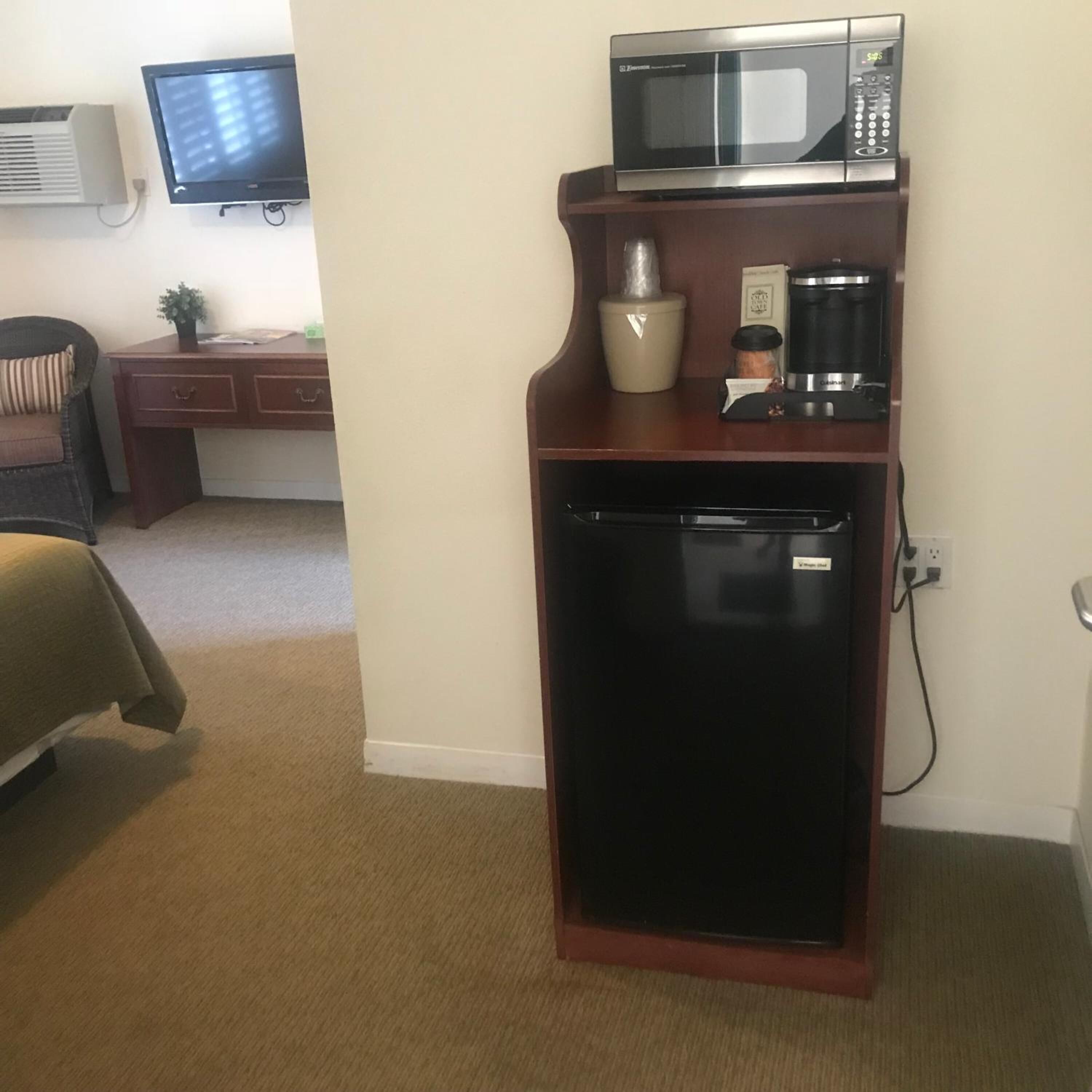 A compact kitchenette with a microwave, coffee maker, and refrigerator.