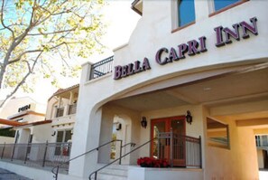 Exterior del Bella Capri Inn, destacando una entrada con un balcón y una escalera que conduce a la entrada principal.