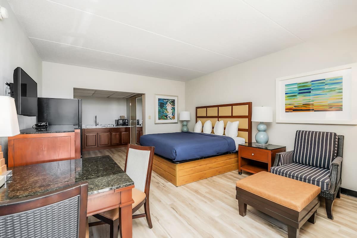Une chambre d’hôtel équipée d’un lit, d’un bureau, d’une chaise, d’une télévision, d’une lampe et d’œuvres d’art accrochées aux murs.