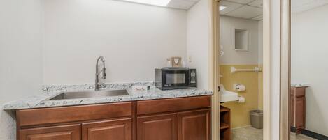 A kitchen with a granite countertop, stainless steel sink, and wooden cabinets.