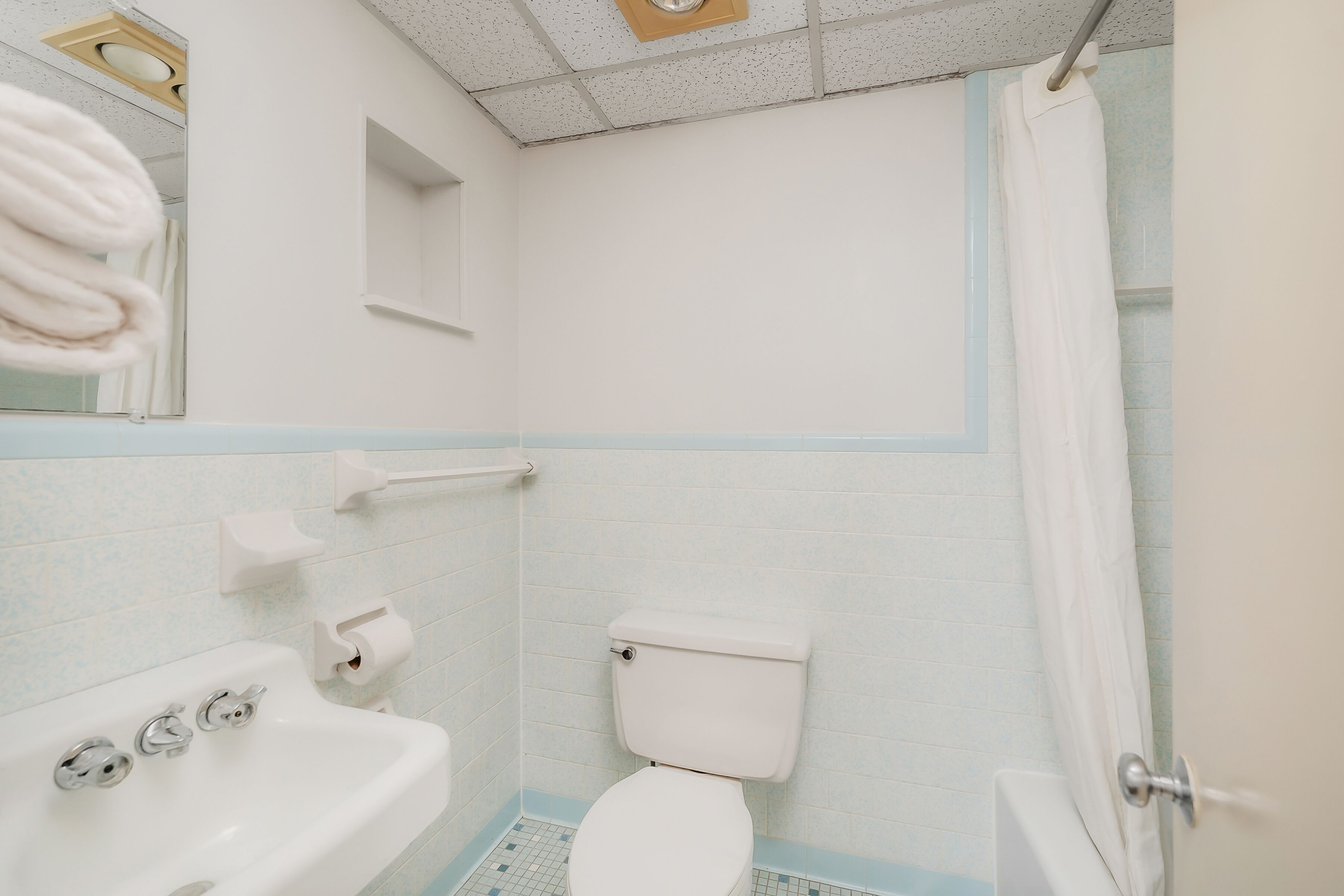 A bathroom with a white sink, toilet, and shower curtain.