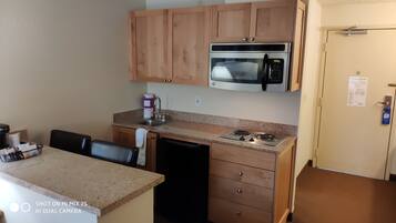 Una cocina compacta con microondas, estufa y armarios de madera.