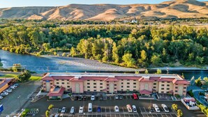 Un hôtel doté d’un parking, situé près d’une rivière, avec des collines en arrière-plan.