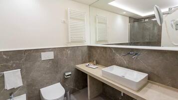 A modern bathroom with a large mirror, a rectangular sink, a toilet, and a shower area.