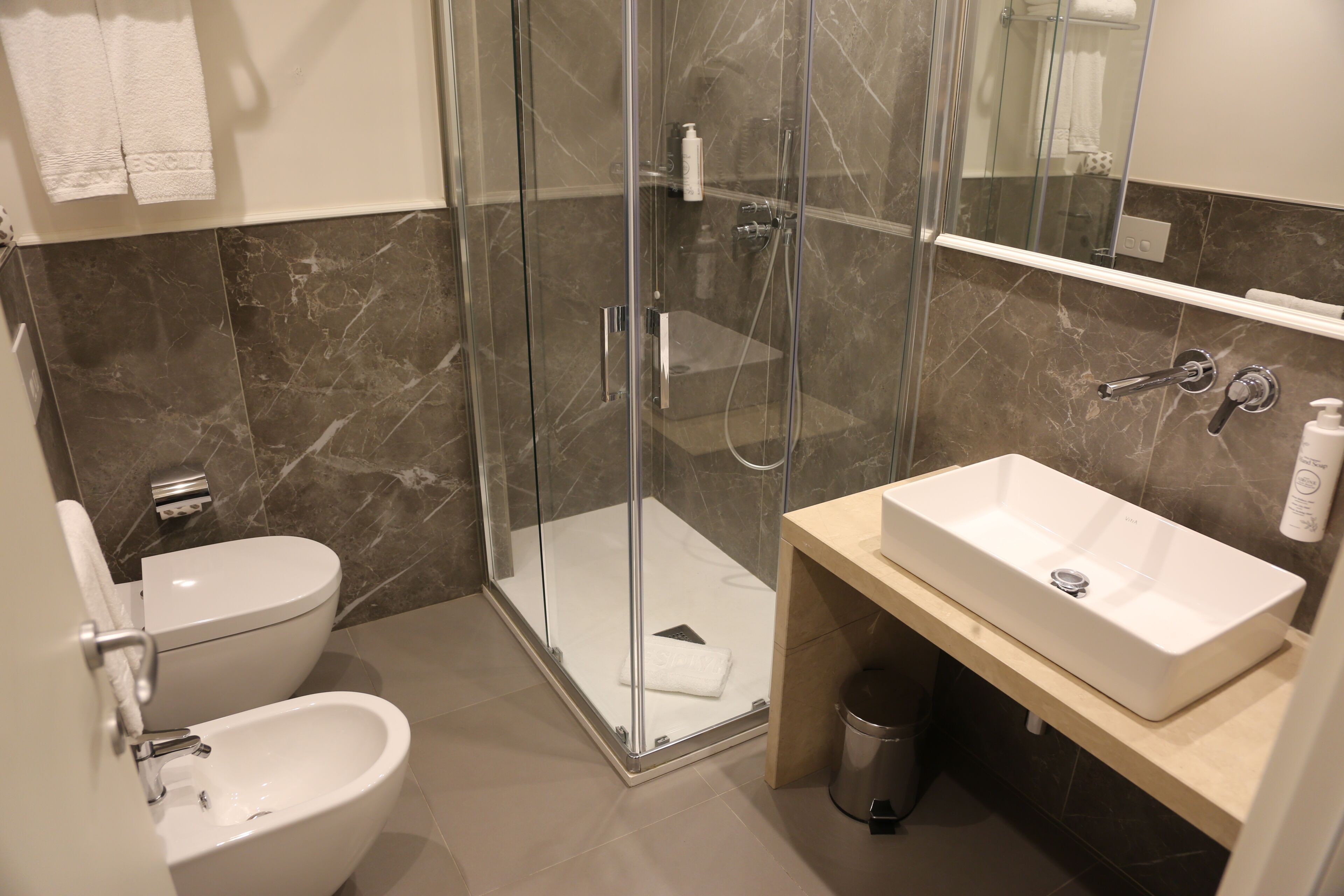 A modern bathroom with a glass-enclosed shower, a toilet, a bidet, and a sink with a vanity.
