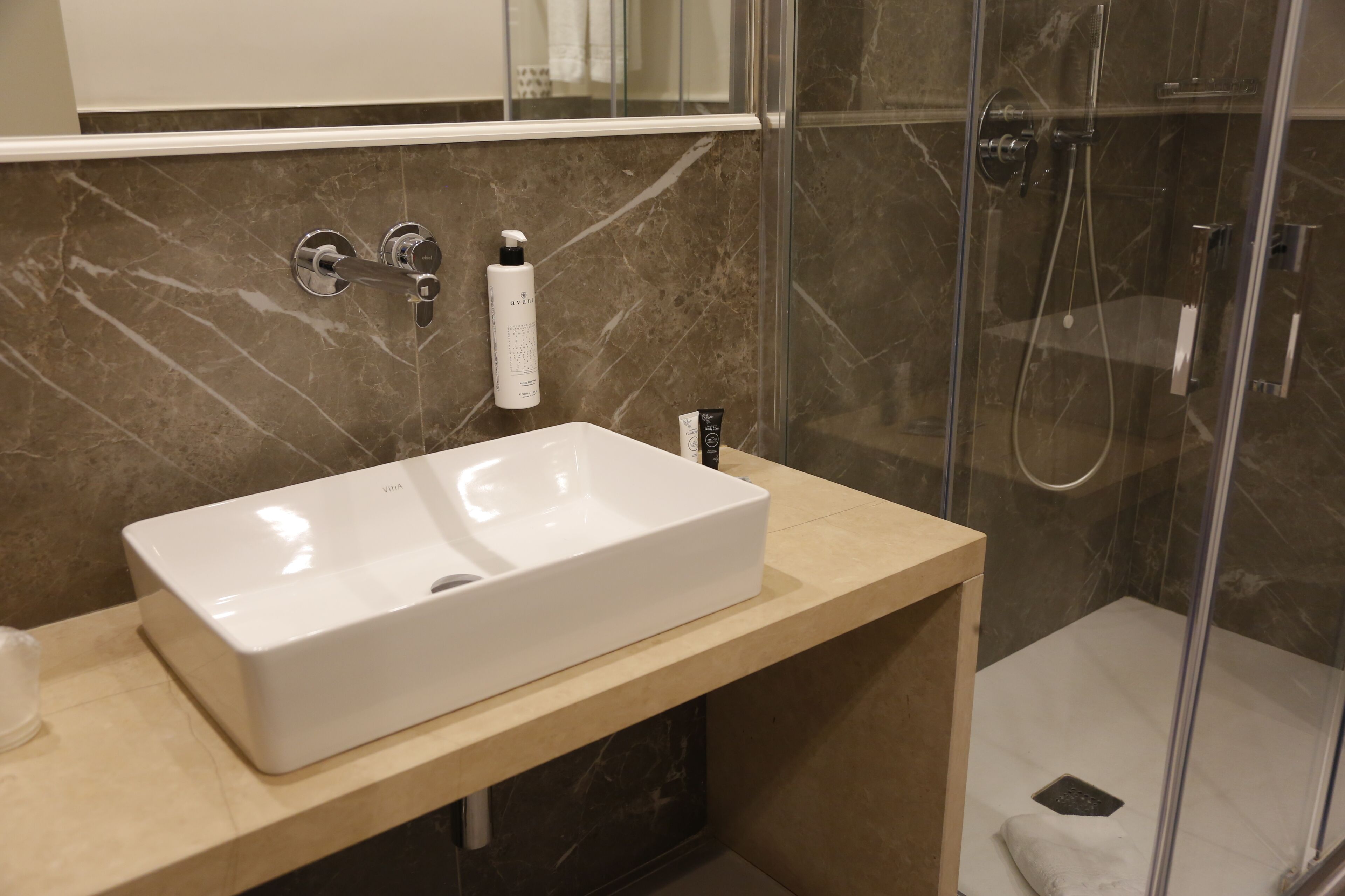 A bathroom with a white sink, a mirror above it, and a shower area with a glass door.
