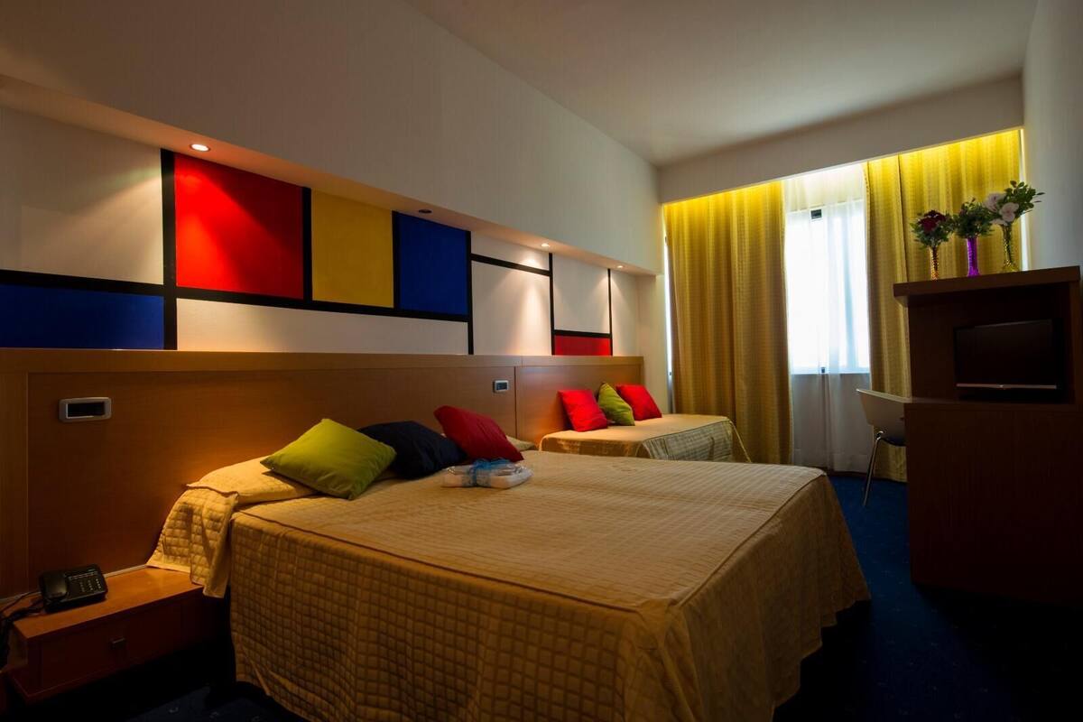 A hotel room with two beds, a TV, and a desk with a telephone.