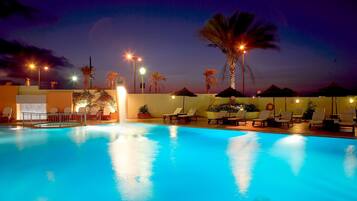 Una piscina al aire libre, sombrillas, sillones reclinables de piscina