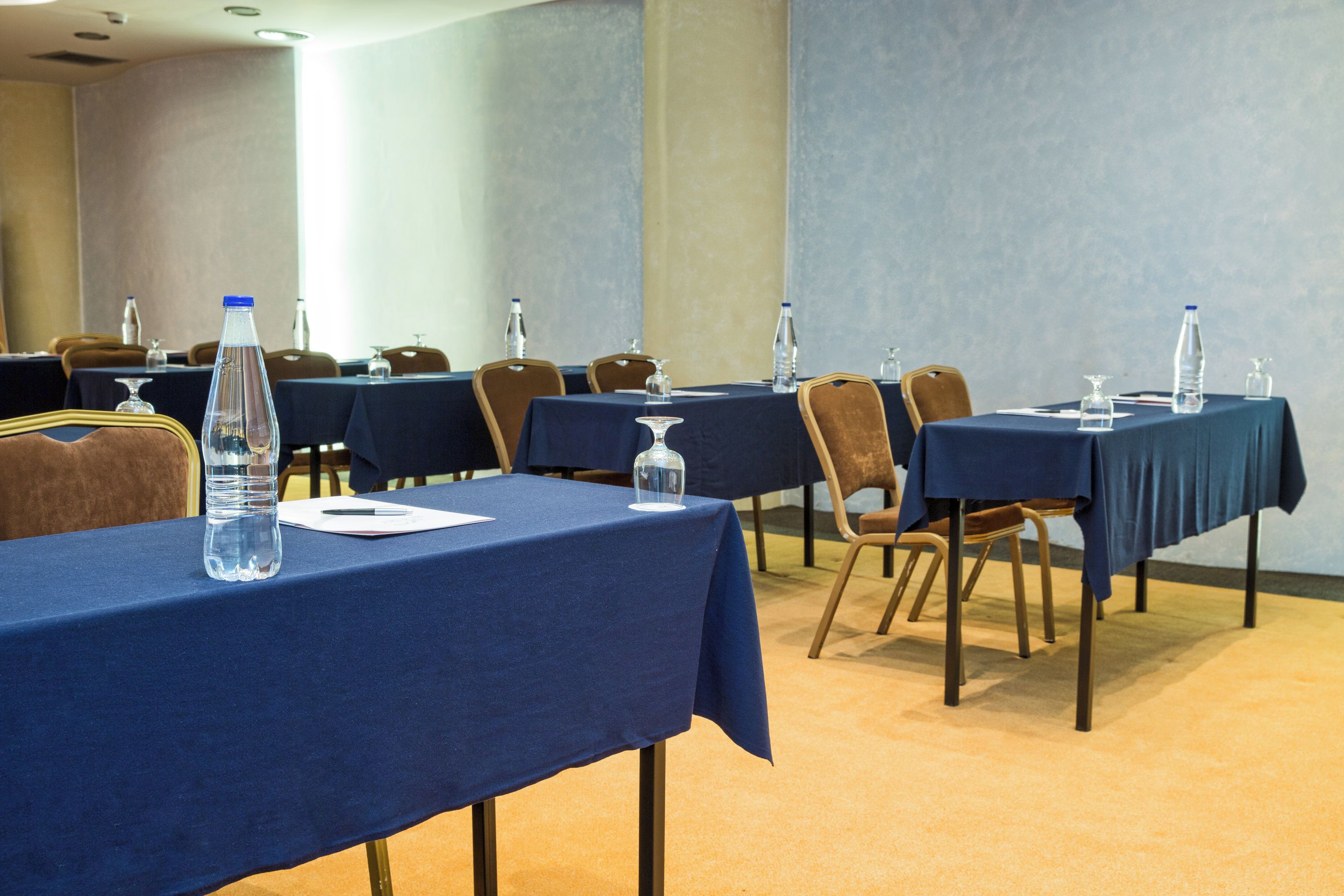 A conference room with tables set up for meetings, equipped with water bottles and glassware.
