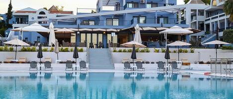 A modern hotel with a swimming pool, outdoor seating, and a staircase leading to the upper floors.