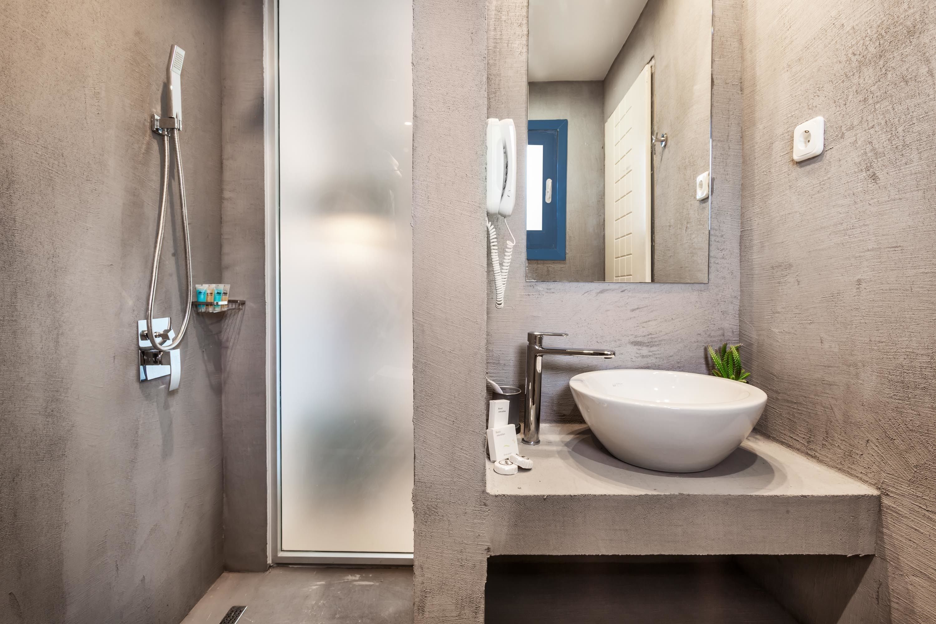 A modern bathroom with a large sink, a handheld showerhead, and a mirror.
