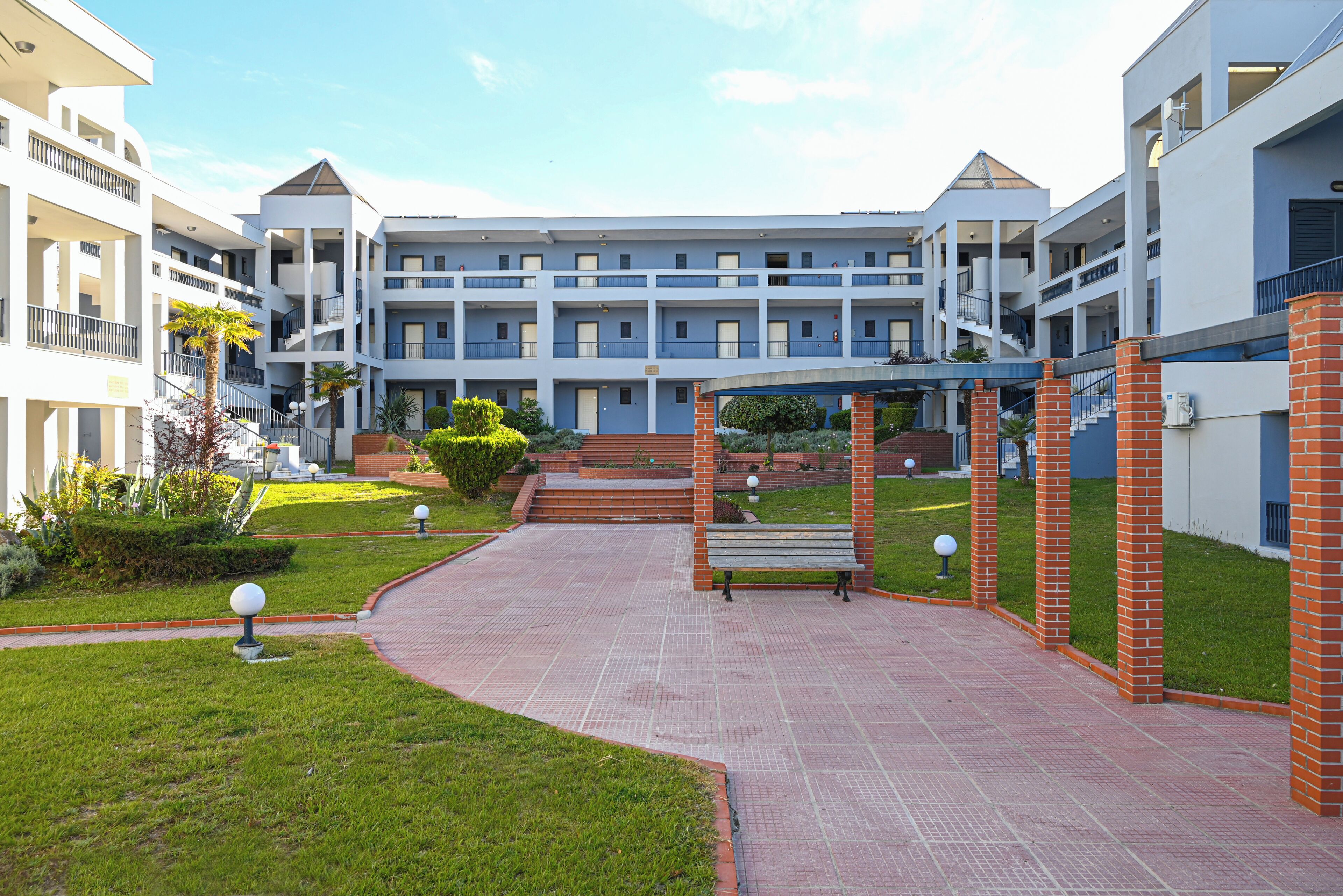 A multi-story hotel with a central courtyard, a staircase, and a bench.