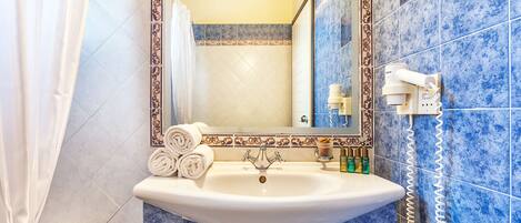 Un baño con lavamanos, espejo y paredes con azulejos azules.